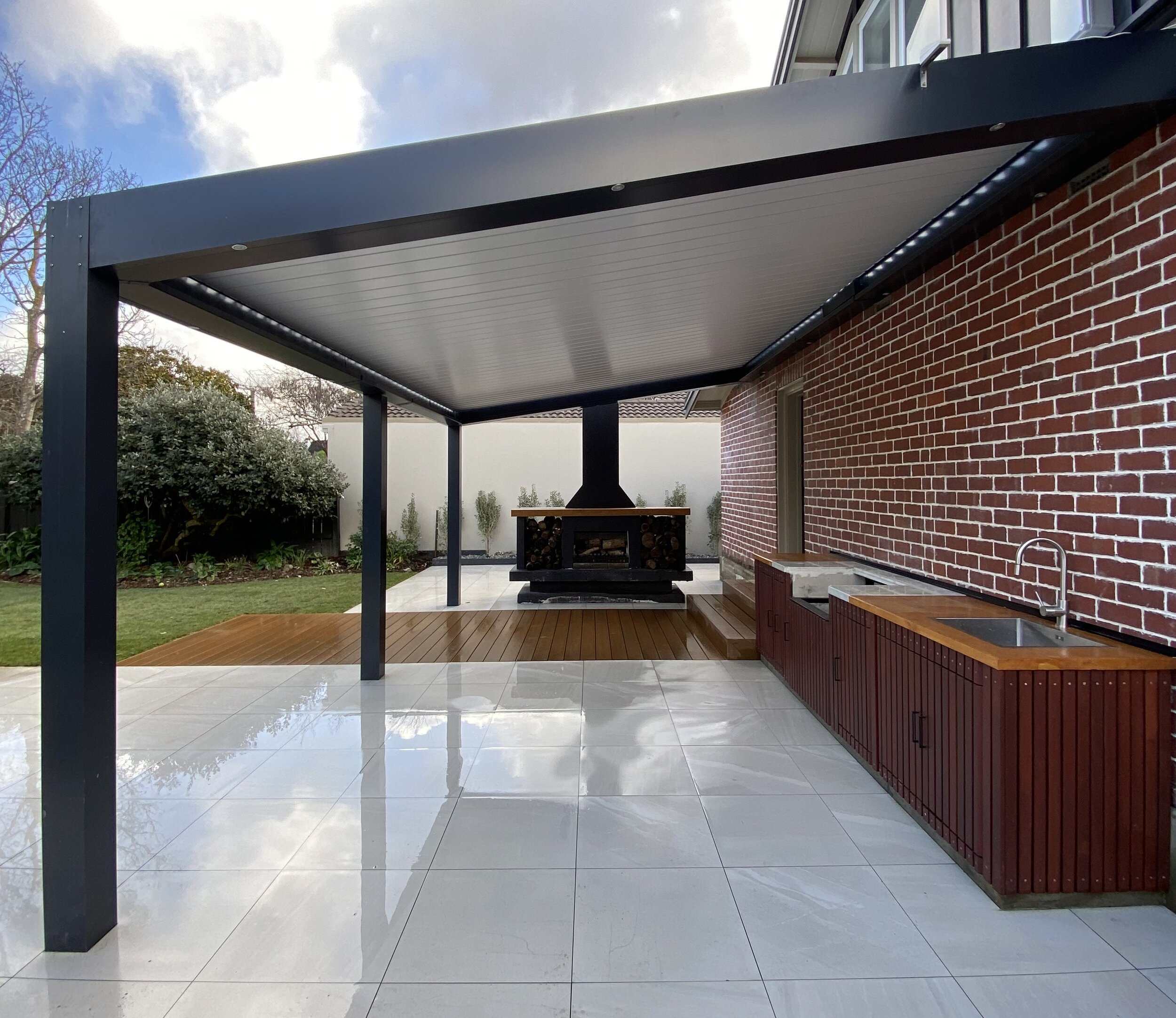 A modern outdoor kitchen with a built-in grill and concrete countertops at dusk.
